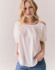 Front view of Northridge Tee in white with cold shoulder cutout and flowy fit and blue jeans against a plain background