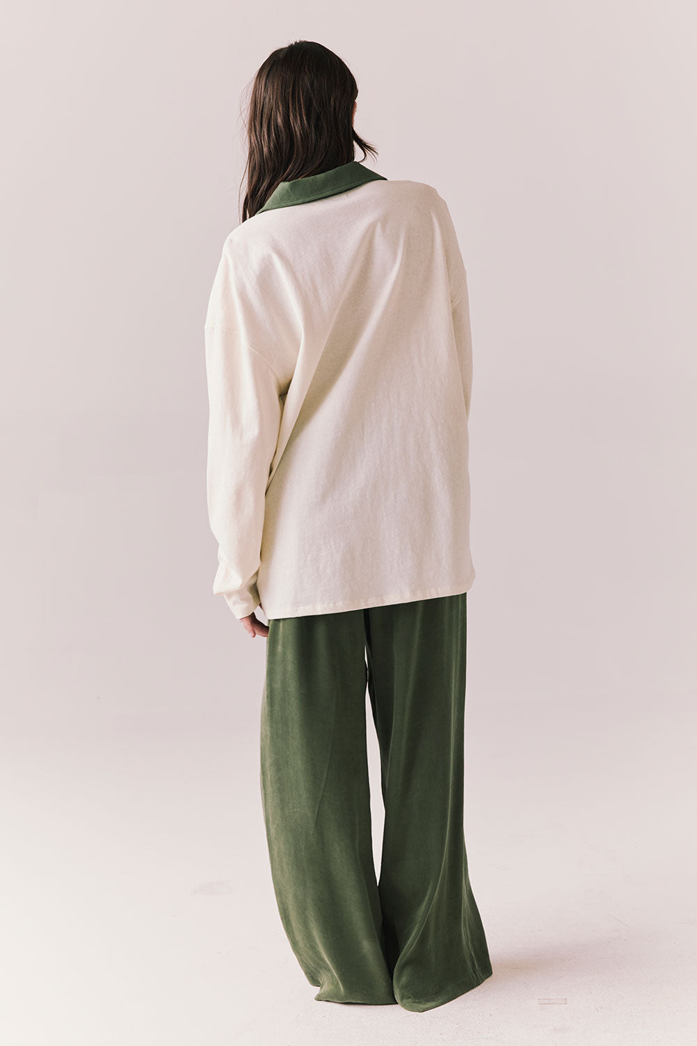 Full back view of woman wearing the color-blocked Chico Long Sleeve White and Green Rib Pullover and green pants on a white background