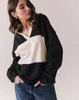 Side view of woman wearing a black and white Chico long sleeve with striped design against a plain background