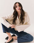 Woman sitting on the floor wearing the Humboldt long sleeve in starry white with soft cotton texture and blue jeans against a white background