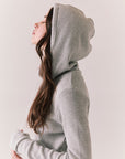 Side view of model wearing Merced Hoodie Dress in Heather Grey with hood and thermal knit texture against a plain background