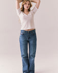 Full body view of model wearing Fresno tee in white with scoop neckline and fitted silhouette and blue jeans against a plain background
