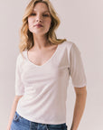 Front view of model wearing Fresno tee in white with scoop neckline and fitted silhouette and blue jeans against a plain background