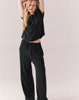Full front view of model wearing Lee Trouser in True Black with high-rise fit and wide-leg silhouette with matching Davis top against a plain background