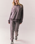 Full front view of Maritime Pullover in fig (deep purple) with relaxed fit and knit texture with matching Bay joggers against a plain background