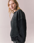 Side view of Maritime Pullover in True Black with relaxed fit and knit texture against a plain background