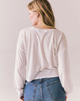 Back view of women wearing the Hartt long sleeve in white with cotton texture and clean silhouette and blue jeans against a plain background