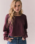 Front view of model wearing the Hartt long sleeve tee in fig (deep purple) with clean silhouette and blue jeans, against a plain background.