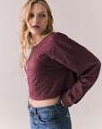 Side view of model wearing the Hartt long sleeve tee in fig (deep purple) with clean silhouette and blue jeans, against a plain background