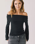 Front view of woman wearing Chaser’s Pixie True Black Long Sleeve with off-shoulder design on a white background