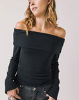 Front view of woman wearing Chaser’s Pixie True Black Long Sleeve with off-shoulder design on a white background