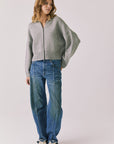 Full body view of woman wearing Chaser’s Heather Grey Luck Zip Up Cardigan Sweater and blue jeans on a white background