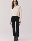 Full body view of woman wearing Chaser’s Warm White Luck Zip Up Cardigan Sweater with black pants and black boots on a white background