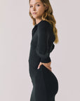 Side view of woman wearing Chaser’s Lara True Black Mini Dress with long sleeves on a white background