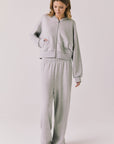Full body view of woman wearing Chaser’s Kiki Heather Grey Zip Up Hoodie with matching Daze Heather Grey Joggers on a white background