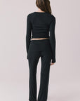 Full body back view of woman wearing Chaser’s True Black Mantra Legging with matching Porta True Black Long Sleeve on a plain background