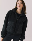 Front view of woman wearing Chaser’s Juno True Black Fleece Jacket on a plain background