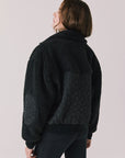 Back view of woman wearing Chaser’s Juno True Black Fleece Jacket on a plain background
