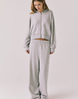 Full body view of woman wearing Chaser’s Daze Heather Grey Joggers and matching Kiki Heather Grey Zip Up Hoodie on a white background
