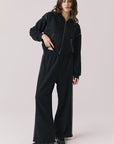 Full body view of woman wearing Chaser’s Daze True Black Joggers and matching Kiki True Black Zip Up Hoodie with sequin details on a white background