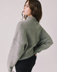 Back view of woman wearing Chaser’s Frankie Heather Grey Pullover Sweater with black pants on a white background