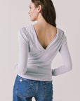 Back view of woman wearing Chaser’s Owen Moonstone Grey Long Sleeve top featuring a low-cut open back design on a light gray background