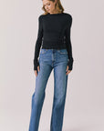 Full body view of woman wearing Chaser’s Owen True Black Long Sleeve top and blue jeans on a light gray background