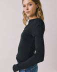 Side view of woman wearing Chaser’s Owen True Black Long Sleeve top showing soft drape and lightweight texture on a light gray background