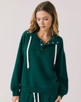 Front view of woman wearing Chaser’s City Blue Grass Green Half Zip Pullover with white drawstrings on a plain background