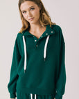 Front view of woman wearing Chaser’s City Blue Grass Green Half Zip Pullover with white drawstrings on a plain background