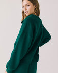 Back view of woman wearing Chaser’s City Blue Grass Green Half Zip Pullover with white drawstrings on a plain background
