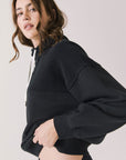 Side view of woman wearing Chaser’s City True Black Half Zip Pullover with white drawstrings on a plain background