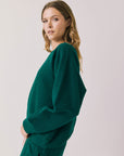 Side view of woman wearing Chaser’s Cello Blue Grass Green Pullover on a white background