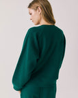Back view of woman wearing Chaser’s Cello Blue Grass Green Pullover on a white background
