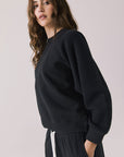 Side view of woman wearing Chaser’s Cello True Black Pullover on a white background
