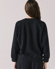 Back view of woman wearing Chaser’s Cello True Black Pullover on a white background