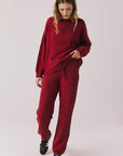 Full body view of woman wearing Chaser’s Miller Purple-Red Fig Pullover Sweater with matching Monica Purple-Red Fig Joggers on a white background