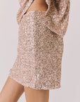 Side view of woman wearing Chaser’s Jayde Bronze Brown Mini Skirt with matching Davis Bronze Brown Tee on a light gray background