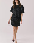 Full body view of woman wearing Chaser’s Jayde True Black Mini Skirt with matching Davis True Black Tee on a light gray background