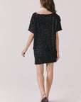 Full body back view of woman wearing Chaser’s Jayde True Black Mini Skirt with matching Davis True Black Tee on a light gray background