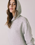 Woman wearing Chaser's Aster Heather Grey Hoodie Dress with hoodie up on a plain background