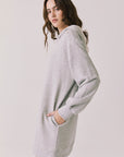 Side view of woman wearing Chaser's Aster Heather Grey Hoodie Dress with hand in pocket on a plain background
