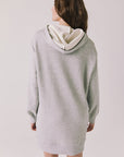 Back view of woman wearing Chaser's Aster Heather Grey Hoodie Dress on a plain background