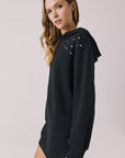 Side view of woman wearing Chaser Aster True Black Hoodie Dress with decorative elements on shoulders on a plain background