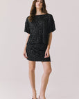 Full body view of woman wearing Chaser’s Davis True Black Tee and matching Jayde True Black Mini Skirt on a light gray background