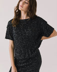 Front view of woman wearing Chaser’s Davis True Black Tee and matching Jayde True Black Mini Skirt on a light gray background