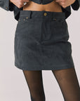 Front view of woman wearing Chaser’s Brooke True Black Mini Skirt on a light background