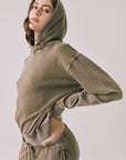 Side view of woman wearing Chaser’s Ginger Brown Martini Pullover Hoodie with hood up on a light pink background