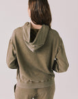 Back view of woman wearing Chaser’s Ginger Brown Martini Pullover Hoodie on a light pink background