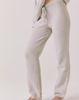 Side view of woman wearing Chaser’s Monica Heather Grey Joggers on a white background
